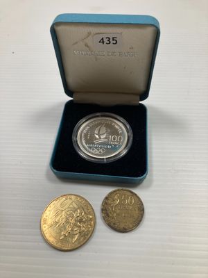 une pièce d'argent et deux pièces d'or dans une boîte bleue
