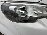close up of the headlight of a white car in a parking lot