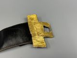 leather belt with a gold buckle on a gray surface