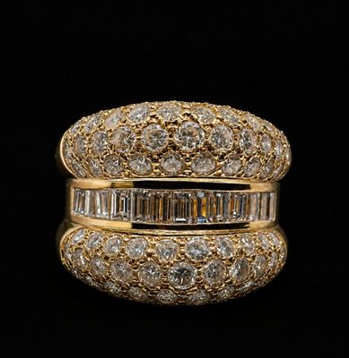 a gold ring with baguets and diamonds on a black background