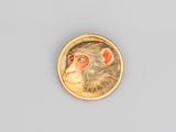 un gros plan du visage d'un singe sur une broche plaquée or