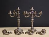 trois chandeliers en argent posés sur une table devant un fond noir
