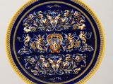 blue and yellow plate with a design on it on a stand