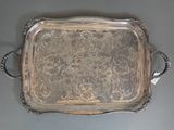 an ornate silver tray with handles and handles on a gray surface