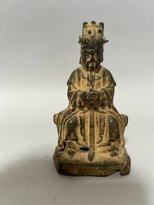 une vieille statue en bronze représentant un homme assis sur une chaise