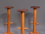 three wooden stools sitting on top of each other on a gray surface
