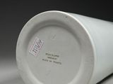 a white cup sitting on a table with a black background