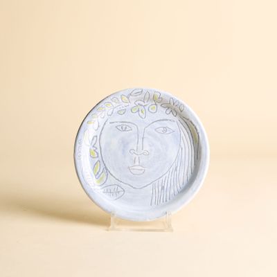 une assiette blanche sur laquelle est représentée une femme