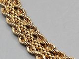 a close up of a gold chain bracelet on a gray surface