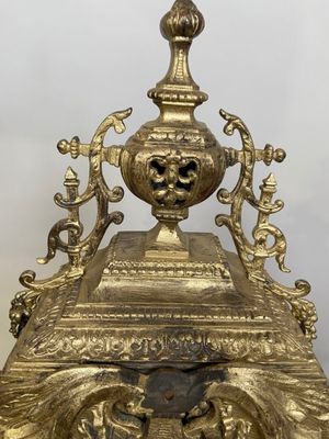 une horloge en or surmontée d'un visage