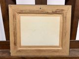 an old picture frame sitting on top of a wooden chair