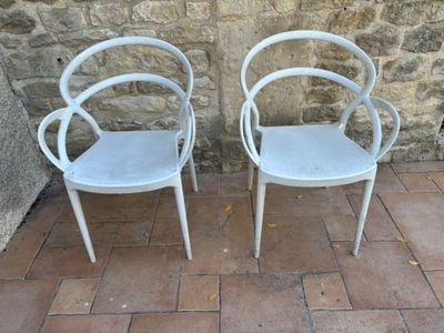 deux chaises blanches placées l'une à côté de l'autre sur un sol en briques