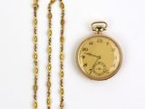 une image représentant une montre de poche en or avec sa chaîne, posée sur une surface blanche