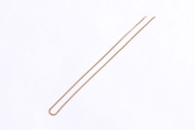 the gold chain is laying on a white surface next to a pair of scissors