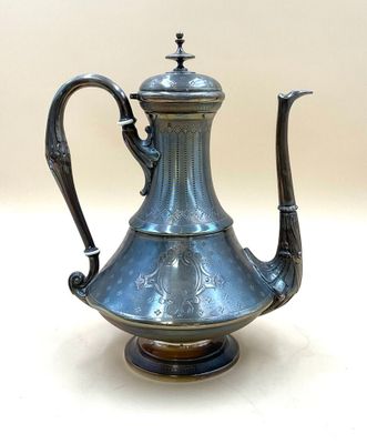 une théière en argent posée sur un socle, sur une table