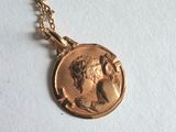 a close up of a gold necklace with a coin on it