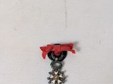 une photo d'une petite médaille entourée d'un ruban rouge