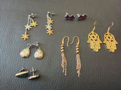 several pairs of earrings are displayed on a black surface