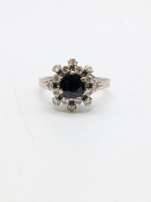 a close up of a black diamond ring on a white surface