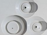 three white plates on a white table with a cup and saucer