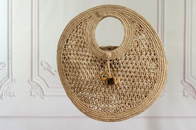 sac en paille tressée accroché à un mur