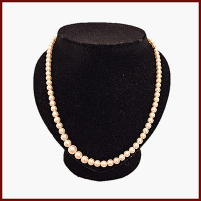 collier de perles présenté sur un mannequin devant un fond rouge