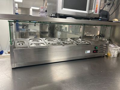 un plan de travail en acier inoxydable dans une cuisine professionnelle, avec une télévision accrochée au mur