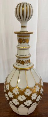 a white and gold vase sitting on a wooden table