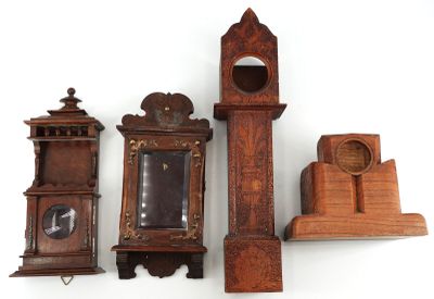 trois horloges en bois et un support d'horloge posés sur une surface blanche
