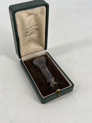 un petit objet métallique dans une boîte verte posée sur une surface blanche