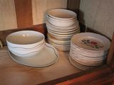 several plates and bowls are stacked on a shelf in a cabinet