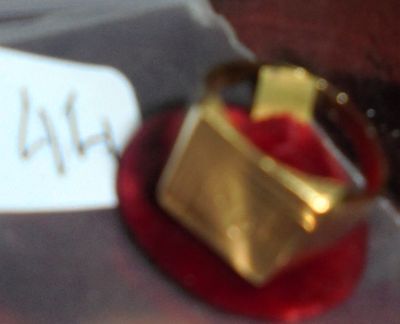 une bague en or posée sur une assiette rouge, avec une étiquette de prix