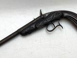 un vieux pistolet avec une poignée en bois sur une surface blanche