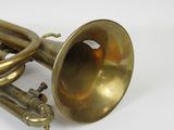 a brass trumpet sitting on a white surface