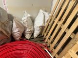 a pile of red hoses next to a pile of wood pallets