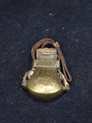 une clochette dorée entourée d'une corde, posée sur une surface noire