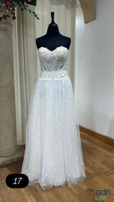 une robe posée sur un mannequin, avec des fleurs en arrière-plan