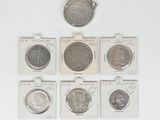 six different types of coins are in small packages on a white surface