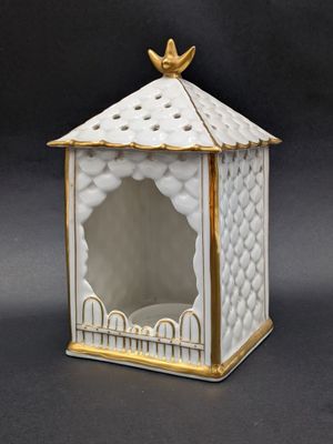 une image représentant une boîte blanche et dorée surmontée d'un oiseau