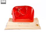 the red louis vuitton bag is sitting on top of a pillow
