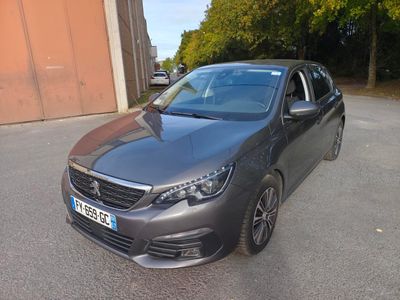 La voiture grise est garée sur le parking à côté de l'immeuble.