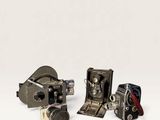 three old cameras sitting on top of a white surface