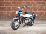 a blue and white motorcycle parked in front of a brick wall