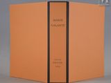 Un livre orange orné d'une bande noire est ouvert sur une table.