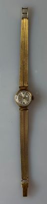 a gold watch on a white surface with a white background