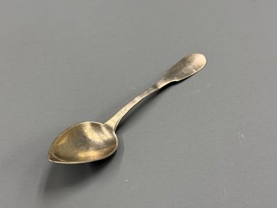 une cuillère en argent posée sur une surface grise, sur fond noir