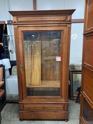 a wooden cabinet with a glass door in the middle of a room
