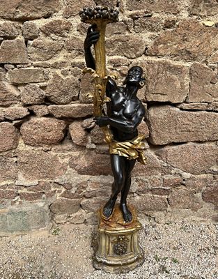 une statue représentant un homme tenant une torche devant un mur de pierre