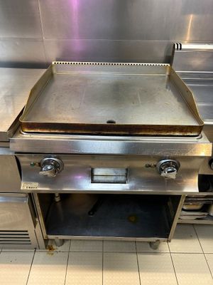 un plan de travail en acier inoxydable équipé d'une plaque de cuisson, dans une cuisine professionnelle