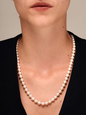une femme portant un collier de perles et un t-shirt noir